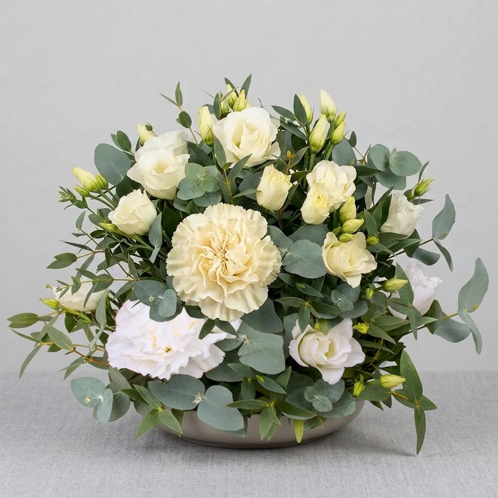 roses blanches et crème s'épanouissant doucement, de lisianthus délicats, d'un grand œillet plissé central, et d'abondants rameaux d'eucalyptus frais vert argenté